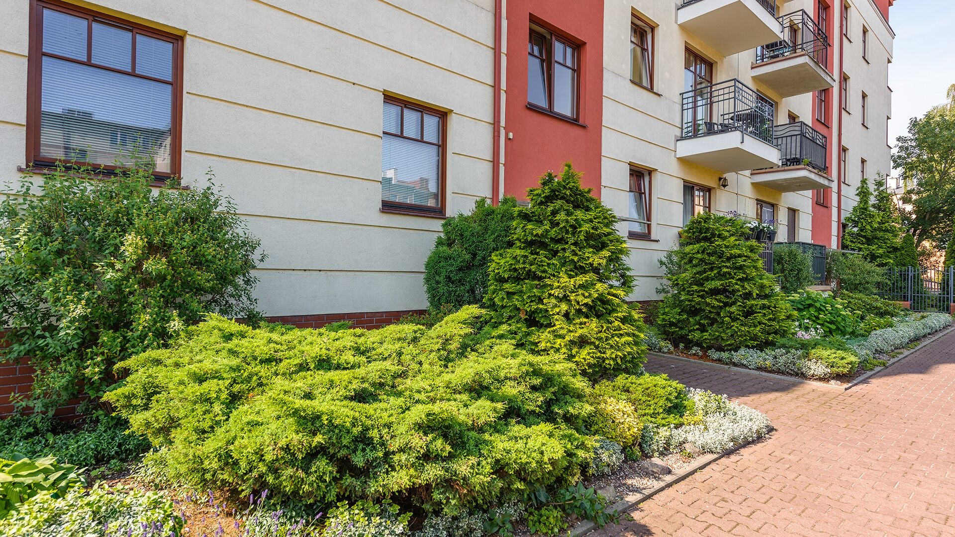 A multi-story residential building with balconies and a well-maintained garden area.