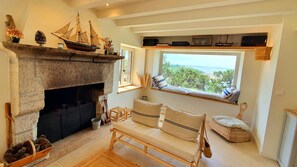 Un salón acogedor con chimenea, un banco y vistas al exterior.
