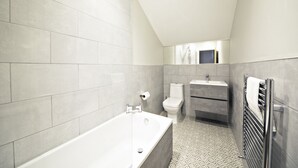 Ein modernes Badezimmer mit einer freistehenden Badewanne, einer Toilette und einem Waschbecken.