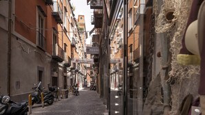A narrow cobblestone street lined with buildings, some with balconies and signage.