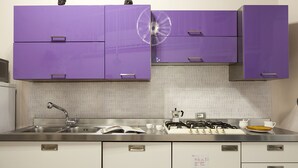 A kitchen with purple cabinets, a stainless steel sink, and a gas stove.