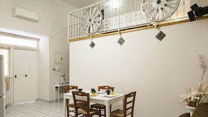 A dining area with a white table and chairs, a ceiling fan, and a staircase with a railing.