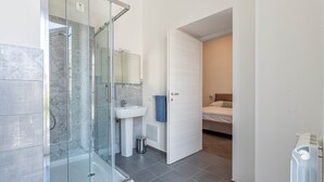 Een badkamer met een douchecabine van glas, een wastafel en een handdoek aan de muur.