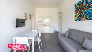 Een moderne woonruimte met een eethoek, een grijze bank en een keuken op de achtergrond.