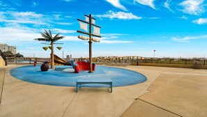 Une aire de jeux avec un toboggan, des balançoires et une structure de jeu.