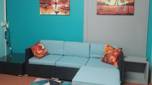 Ein modernes Wohnzimmer mit einer türkisfarbenen Akzentwand, einem hellblauen Sofa und zwei Bildern.