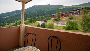 Ein Balkon mit Blick auf eine gebirgige Landschaft und ein mehrstöckiges Gebäude.