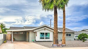 A single-story house with a garage, a covered patio, and a palm tree.