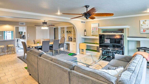 A modern living room with a sectional sofa, a glass coffee table, and a ceiling fan.