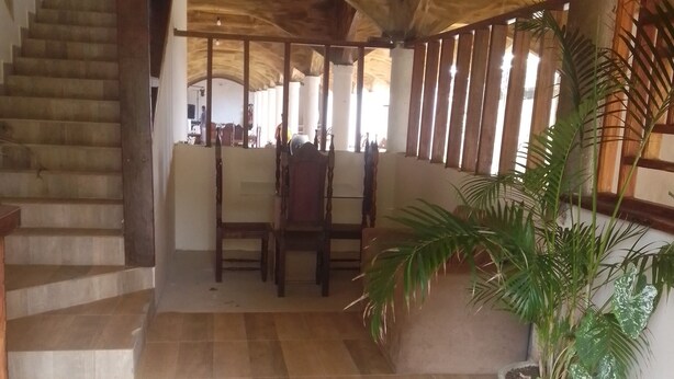A spacious interior with a tiled floor, a staircase, a wooden ceiling, and a potted plant. - Ebora Pousada (Ilhéus)
