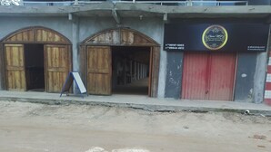 A building with two wooden doors and a red door, a signboard, and a website address. - Ebora Pousada (Ilhéus)