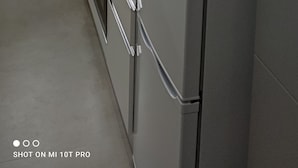 A compact kitchen with white cabinets, a microwave, a stove, and a refrigerator. - Appartamento Lucerelaxcomfort - Studio Flat (Milan)