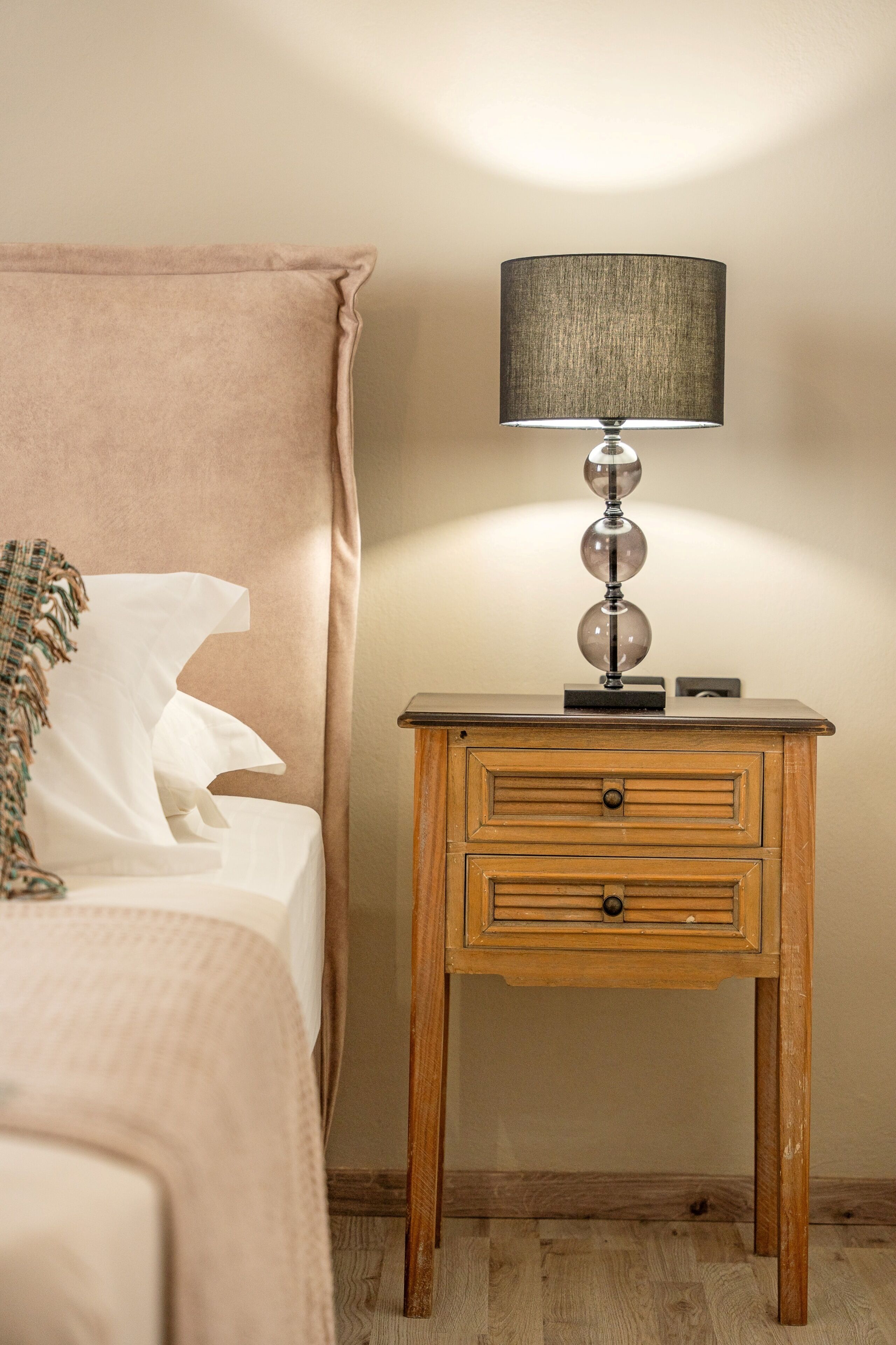 A bedroom with a bed, a bedside table with a lamp, and a wooden nightstand.