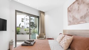 A modern hotel room with a large bed, a chair, a TV, and a view of the outside. - Luxury apartment: air conditioning, swimming pools, heating, gym, fibre optics, garage (Palm-Mar)