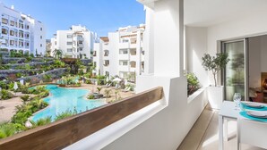 A balcony with a pool, white buildings, and a dining area with a table and chairs. - Luxury apartment: air conditioning, swimming pools, heating, gym, fibre optics, garage (Palm-Mar)