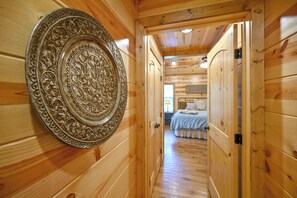 Un couloir en bois mène à une chambre à coucher qui contient un lit et une table de chevet.