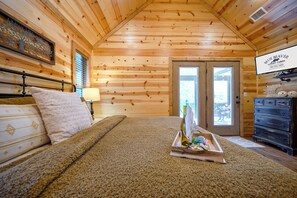 A wooden cabin room with a bed, a dresser, and a window.