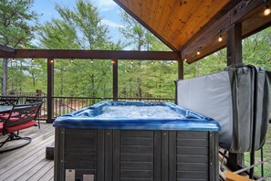 Un bain à remous sur une terrasse en bois, avec vue sur les arbres.