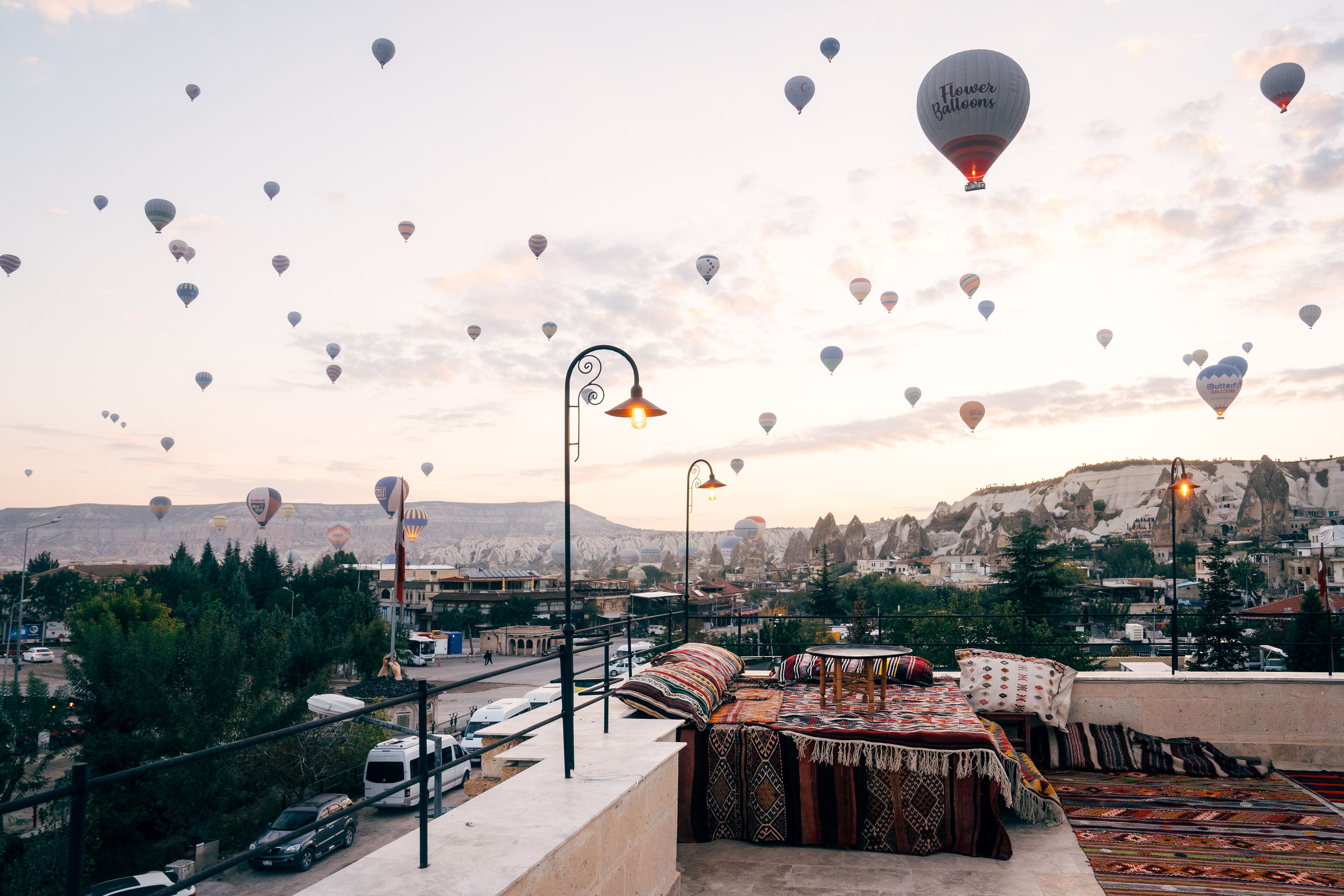A rooftop terrace with a view of a cityscape and mountains, featuring a table and chairs set up for dining.
