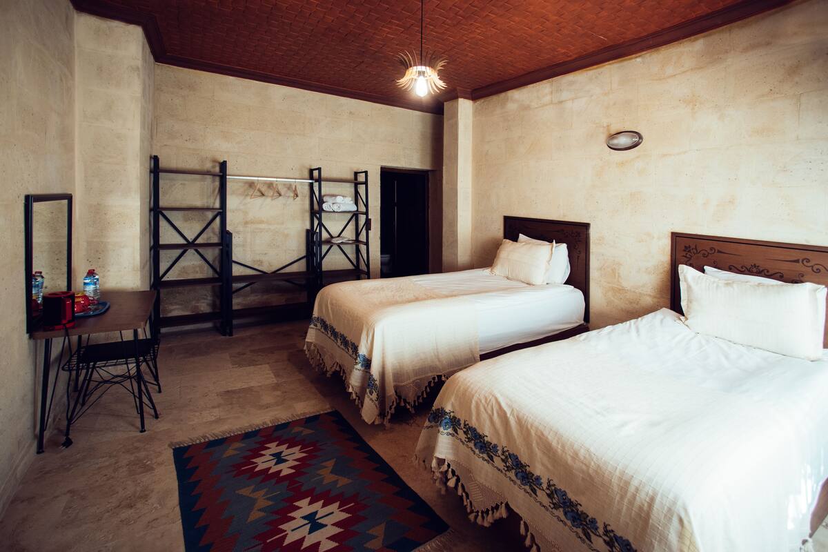 A room with two beds, a desk, a chair, and a patterned rug.
