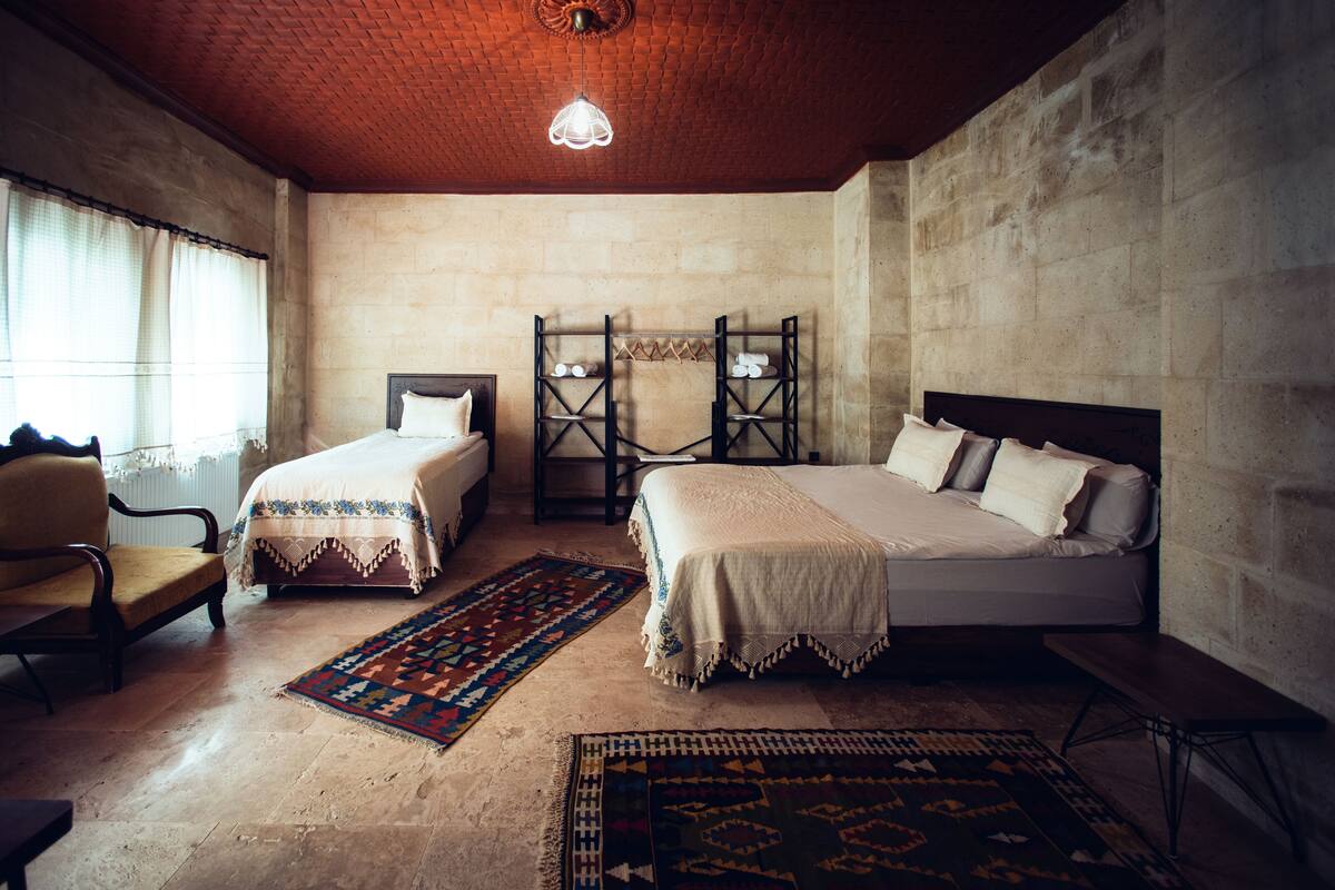 A bedroom with two beds, a chair, and a bench.