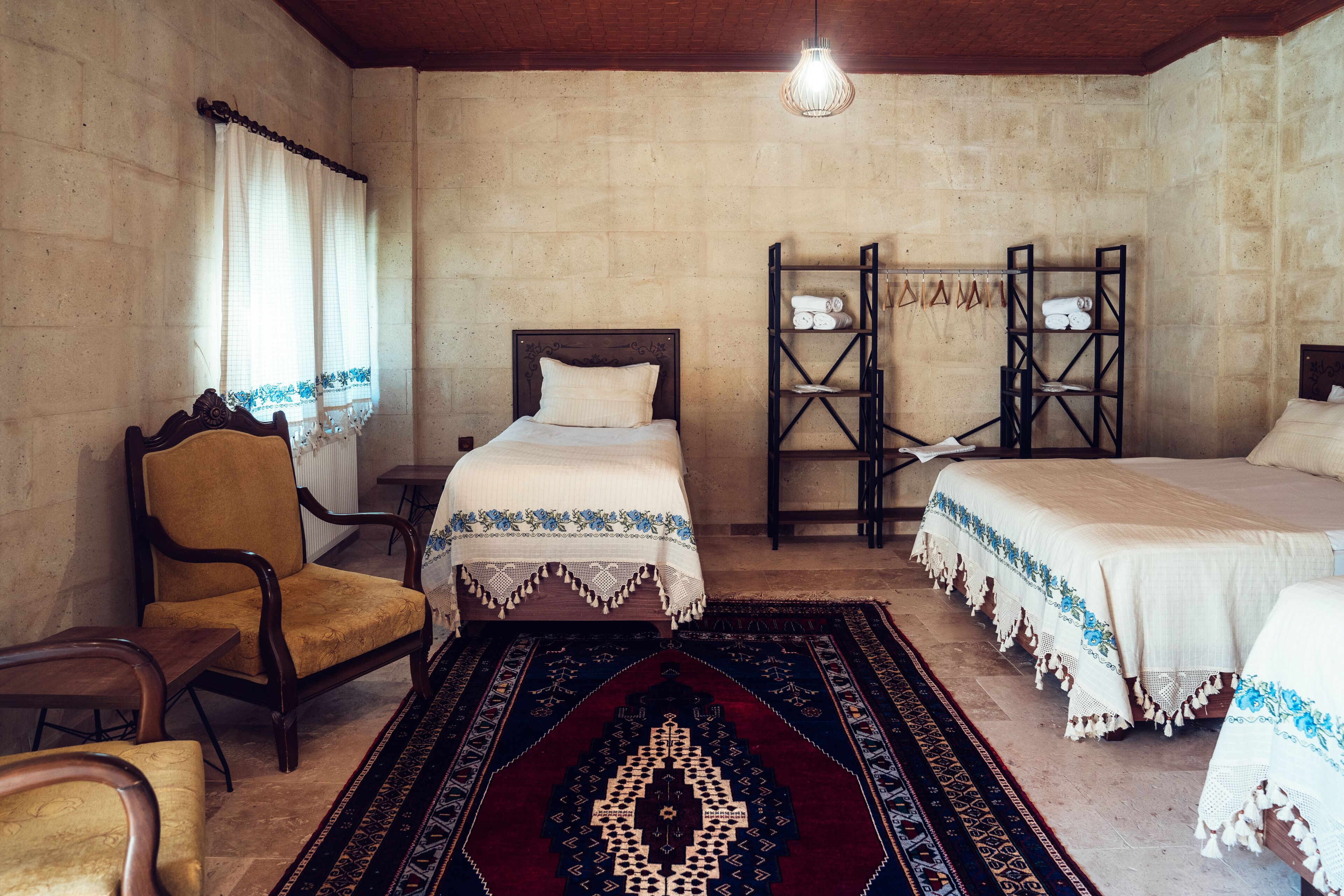 A traditional room with two beds, a wooden chair, and a patterned rug.