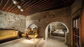A rustic stone-walled room with a bed, two armchairs, and a sofa. - Azalea Terrace Cave Hotel (Nevsehir)