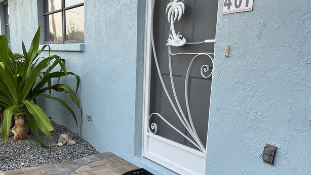 A house with a blue exterior, a decorative door with a number 401 sign, a doormat, and a potted plant. - Close To Beach, 3Bdrm / 2 Bath Duplex (Nokomis)