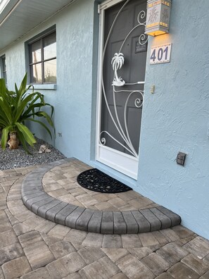 Une maison à l’extérieur bleu, une porte décorative portant le numéro 401, un paillasson et une plante en pot.