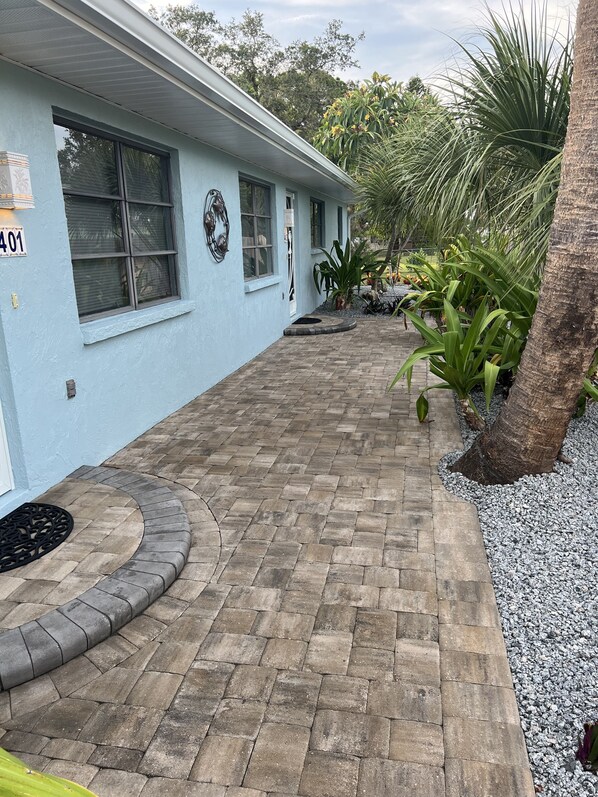 A light blue building with a paved walkway, a number '401' sign, and tropical plants.