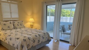 A bedroom with a bed, a nightstand, a lamp, a sliding glass door to a balcony, and a view of greenery outside. - Close To Beach, 3Bdrm / 2 Bath Duplex (Nokomis)