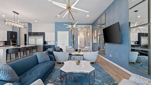 Un salon moderne avec un canapé bleu, une table basse et un téléviseur fixé au mur.