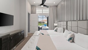 A hotel room with a bed, a sofa, a TV, a ceiling fan, and a view of the outside. - Action-Packed Home w Sports Simulator, Bowling, Gamer BR & Theater - Near Parks (Davenport)