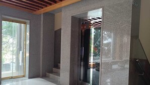 A modern elevator with a glass door, a wooden ceiling, and a tiled floor. - RKN Grand Hotel (Puducherry)