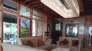 A spacious living area with a high ceiling and large windows, featuring beige sofas and a coffee table. - RKN Grand Hotel (Puducherry)