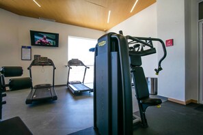 A gym with treadmills, a weight machine, and a wall-mounted TV.