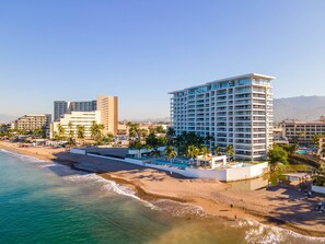 A coastal hotel with a beachfront, multiple buildings, and a pool area.