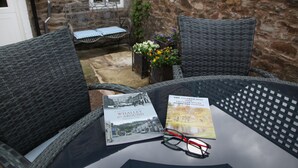 Una taula de vimetra amb dues cadires, un llibre i una parella de gaus.