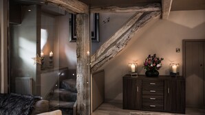 Habitació acollidora amb una porta de vidre, bigues de fusta, una escala i un armari de fusta fosca amb espelmes.