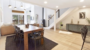 Un comedor amplio con una mesa y sillas de madera, un sofá y una escalera que sube a un nivel superior.