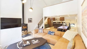 Una sala moderna con chimenea, sofá, mesa de centro y comedor.