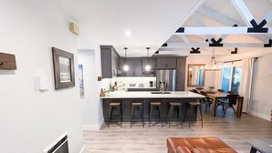 A modern kitchen with a central island, bar stools, and a dining area with a table and chairs. - Seasons 4 #140- Close to Canyon Lodge & The Villag (Mammoth Lakes)