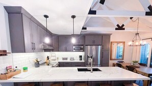 A modern kitchen with a large island, bar stools, stainless steel appliances, and pendant lighting. - Seasons 4 #140- Close to Canyon Lodge & The Villag (Mammoth Lakes)