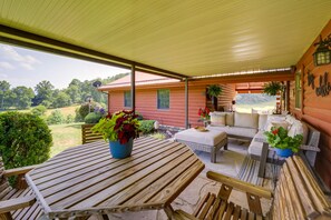 Un patio coperto con tavolo e sedie in legno, un divano e piante in vaso.