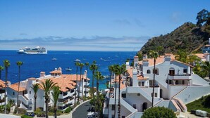 A coastal town with a cruise ship docked, palm trees, and buildings with red-tiled roofs. - Oceanfront view, plus corner patio and golf cart (Avalon)