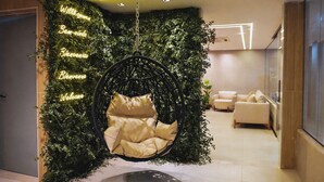 Un interior moderno con una silla colgante, una pared con plantas y una zona de estar con sofá.