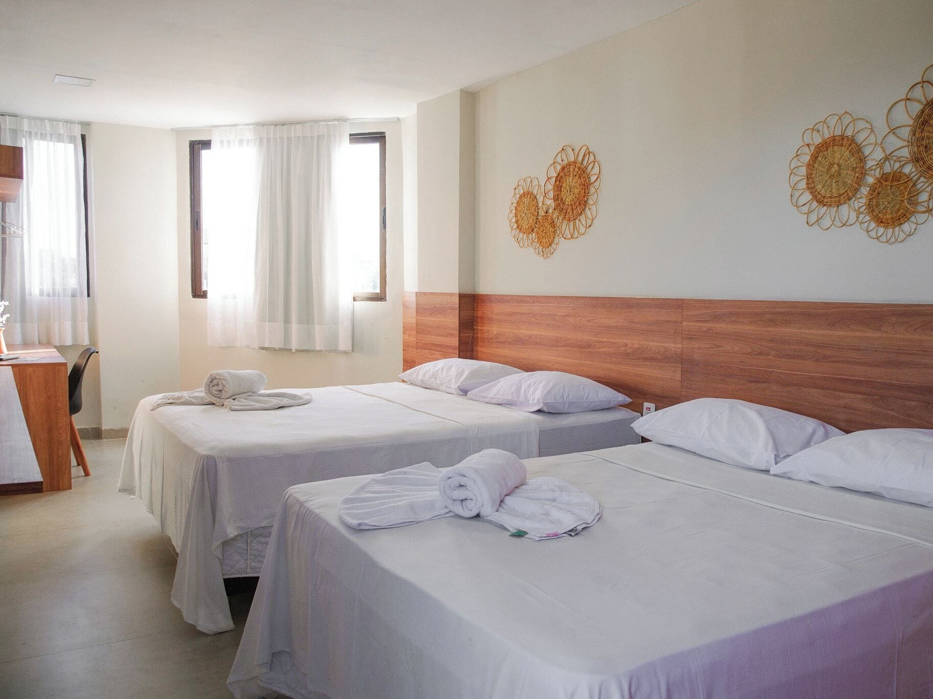 Ein Hotelzimmer mit zwei Betten, einem Holzkopfteil und einer Wanddekoration.