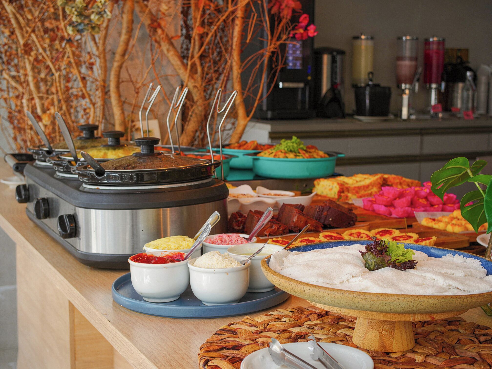 A buffet with various food items and a coffee machine in the background.