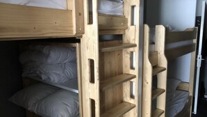Een slaapkamer met stapelbedden van hout en planken.