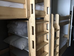 A bunk bed room with wooden bunk beds and shelves.